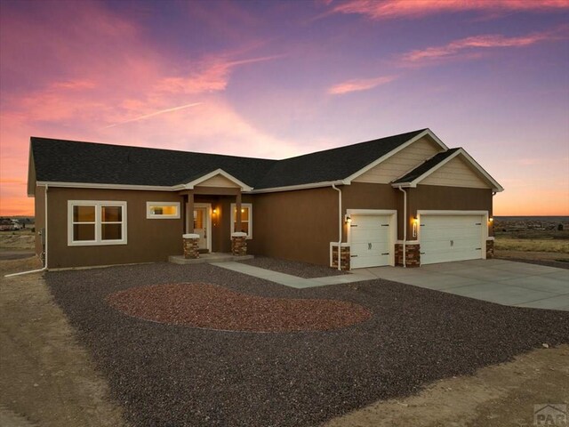 view of front facade featuring stone siding, concrete driveway, an attached garage, and stucco siding