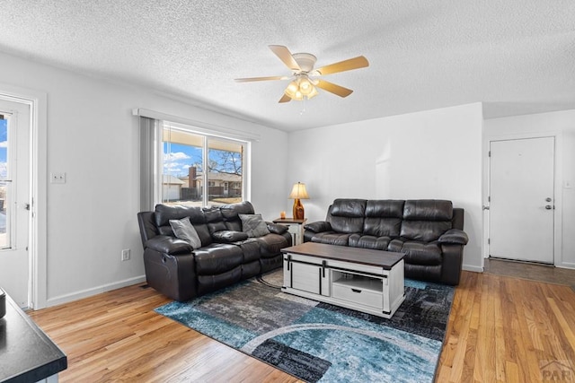 living room with baseboards, a textured ceiling, a ceiling fan, and wood finished floors