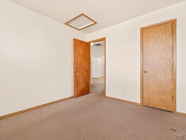 spare room with attic access, baseboards, and light colored carpet