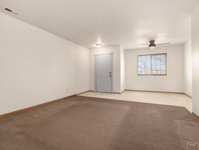 spare room featuring baseboards, visible vents, a ceiling fan, and light colored carpet