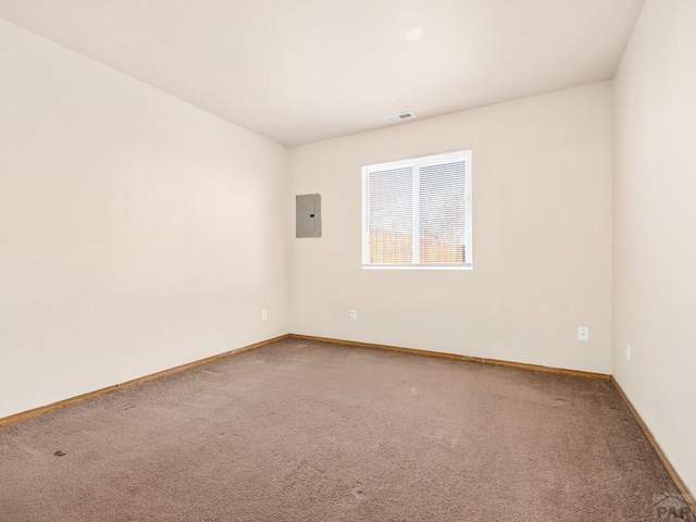 spare room featuring baseboards, carpet, visible vents, and electric panel