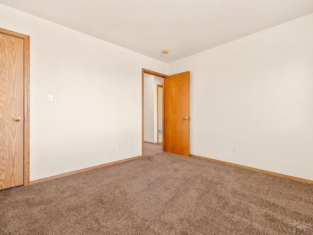 empty room featuring carpet and baseboards