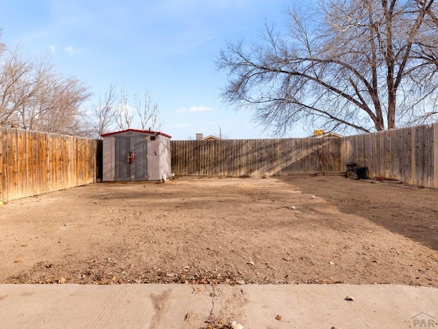 view of yard featuring a fenced backyard, a storage unit, and an outbuilding