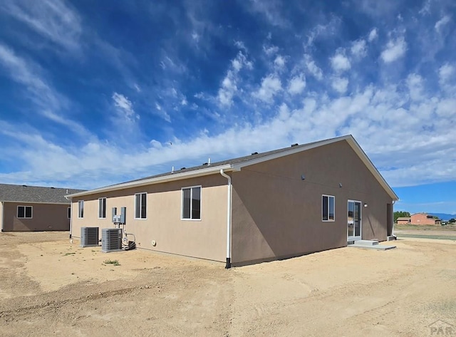 rear view of house featuring stucco siding and central air condition unit