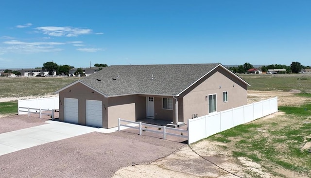 view of front facade with a garage, fence, driveway, and stucco siding