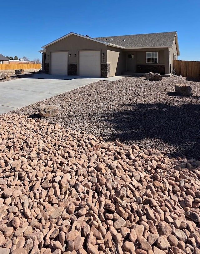 ranch-style house with stucco siding, an attached garage, fence, stone siding, and driveway