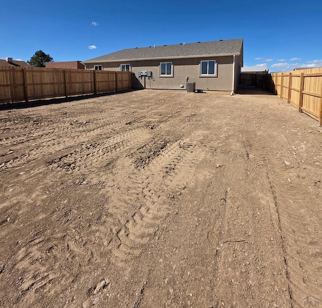 rear view of property featuring a fenced backyard, central AC, and stucco siding