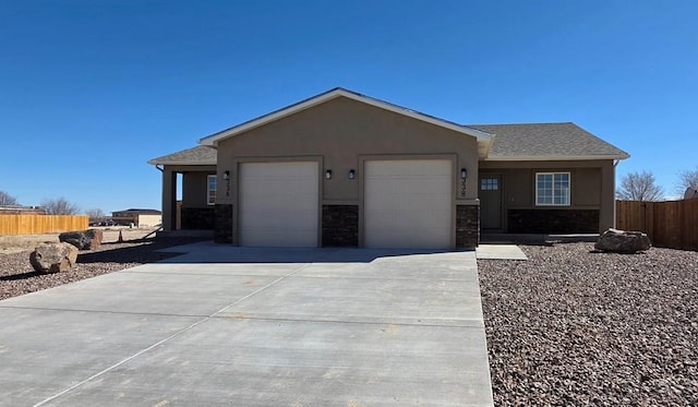 ranch-style home with a garage, fence, concrete driveway, stone siding, and stucco siding