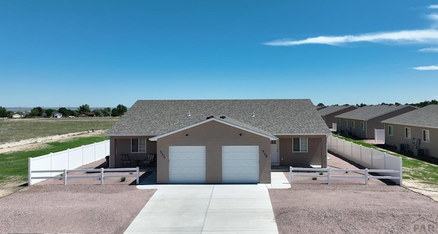 ranch-style home featuring fence private yard, a garage, a shingled roof, concrete driveway, and stucco siding