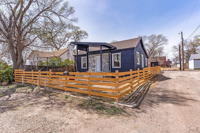 bungalow featuring a fenced front yard and a shingled roof