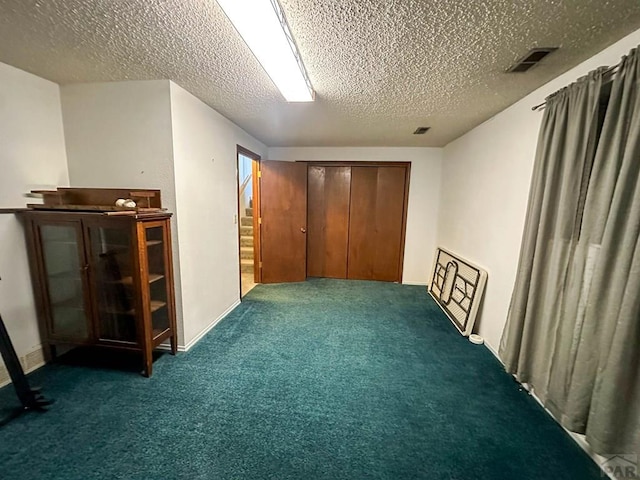 interior space with carpet flooring, a textured ceiling, and visible vents