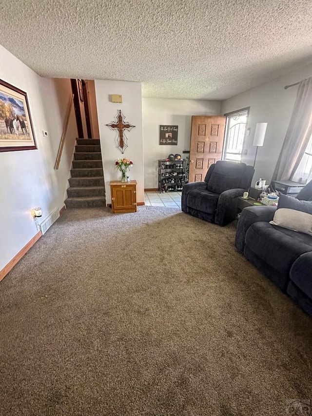 living area featuring light carpet, stairs, a textured ceiling, and visible vents