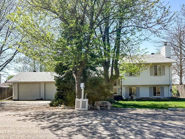 view of front facade with fence, a chimney, and an outdoor structure