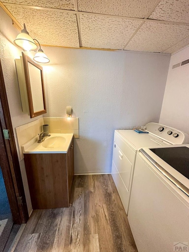 laundry area with washing machine and clothes dryer, laundry area, a sink, visible vents, and dark wood-style floors