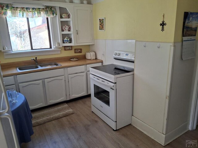 kitchen featuring white electric range, light wood-style floors, white cabinetry, open shelves, and a sink