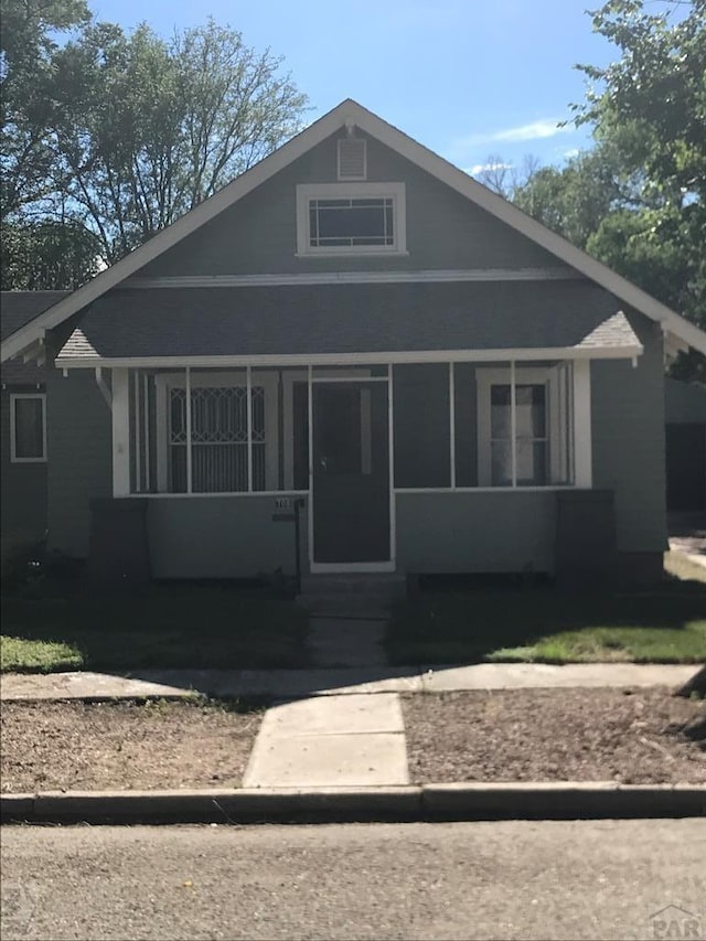 bungalow-style home with an outbuilding, a front lawn, a detached garage, a chimney, and covered porch