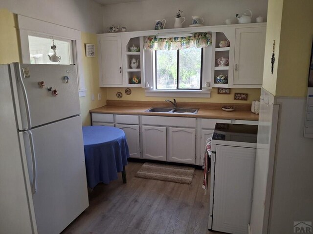 kitchen with open shelves, light countertops, white cabinetry, a sink, and white appliances