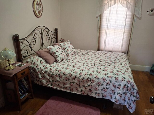 bedroom with baseboards and dark wood-style flooring