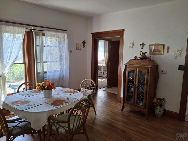 dining space with dark wood-style flooring and baseboards