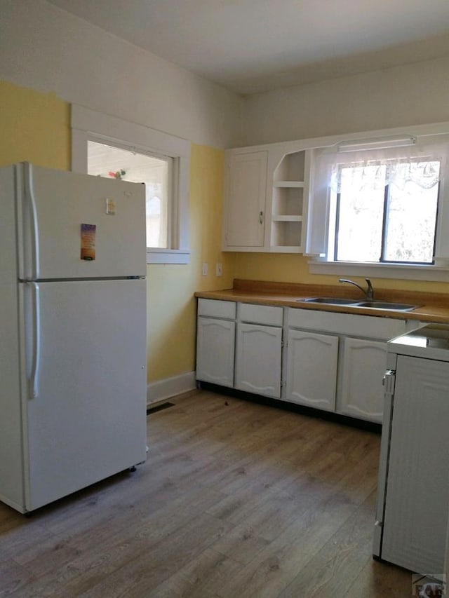 708 7th St, Fowler, CO 81039 - kitchen with freestanding refrigerator, a sink, white cabinets, range, and wood finished floors