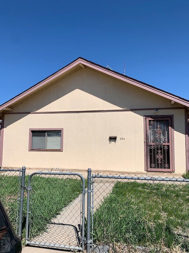 view of side of property featuring a yard, fence, and a gate