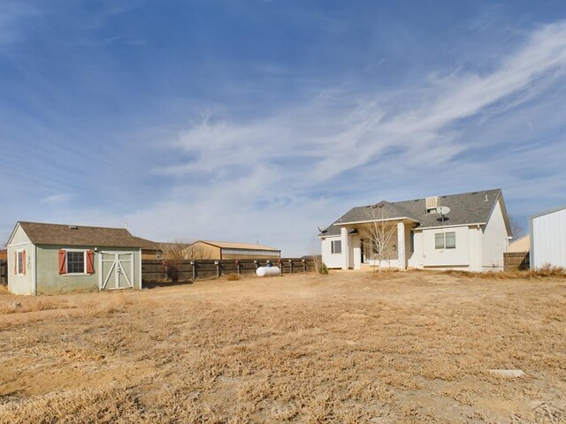 rear view of house featuring an outbuilding and fence