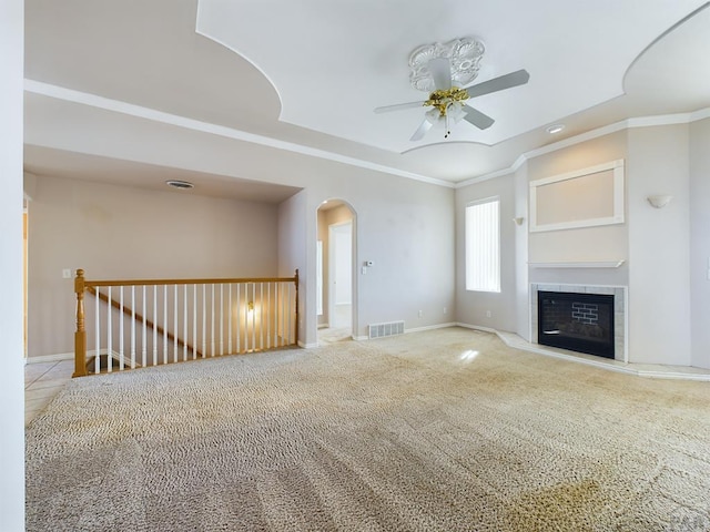 unfurnished living room featuring a tile fireplace, visible vents, crown molding, and baseboards