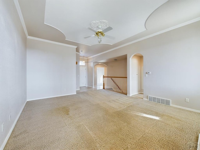 spare room featuring arched walkways, ornamental molding, visible vents, and baseboards