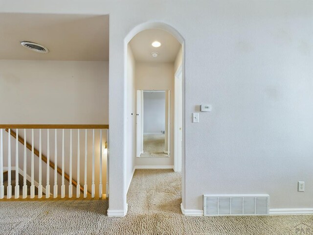 hall with baseboards, visible vents, arched walkways, and carpet flooring