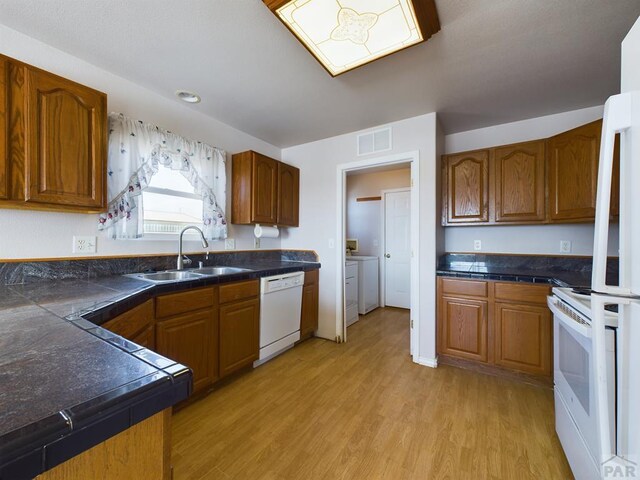 kitchen with white appliances, a sink, visible vents, and brown cabinets