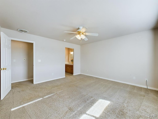 unfurnished bedroom with baseboards, visible vents, a ceiling fan, light colored carpet, and ensuite bath