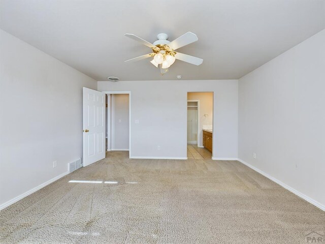 unfurnished bedroom with ceiling fan, ensuite bathroom, light carpet, visible vents, and baseboards