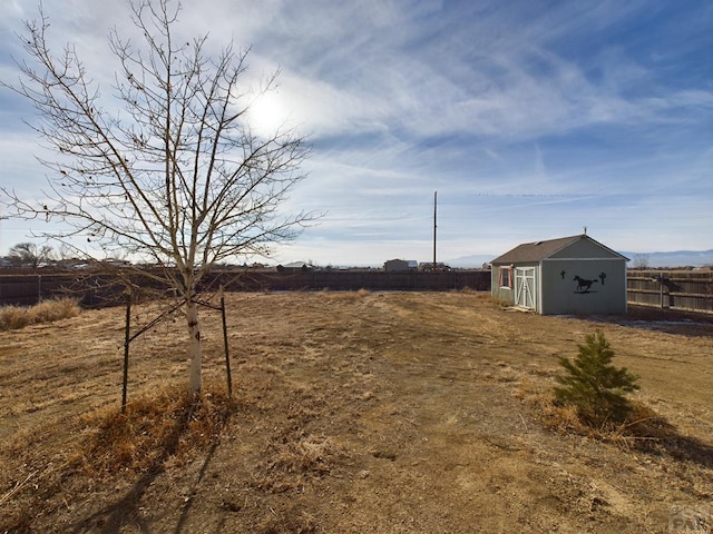 view of yard featuring a rural view, an outdoor structure, and fence