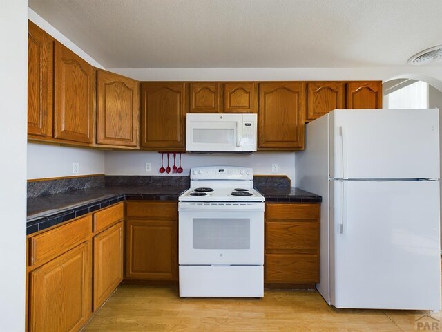 kitchen featuring brown cabinetry and white appliances