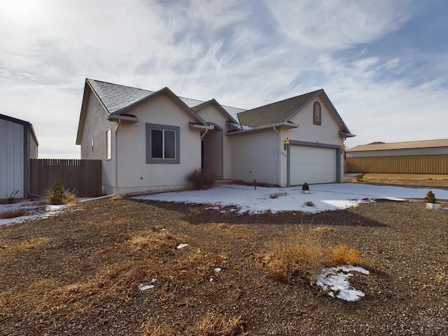 ranch-style house with an attached garage, fence, and stucco siding