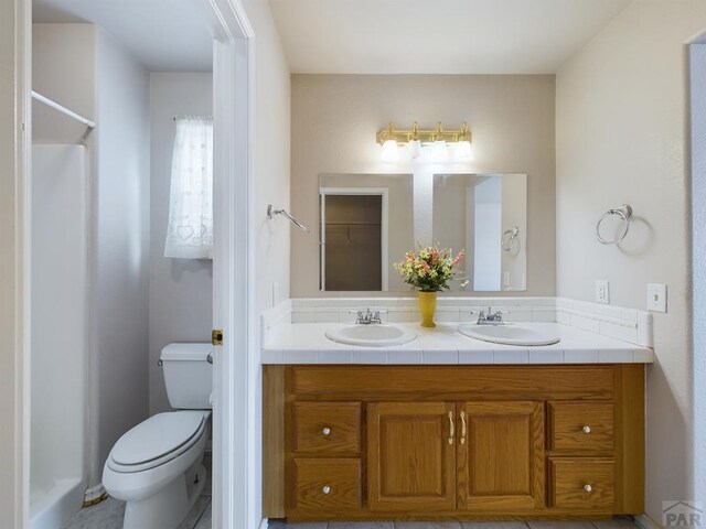 bathroom with a sink, toilet, and double vanity