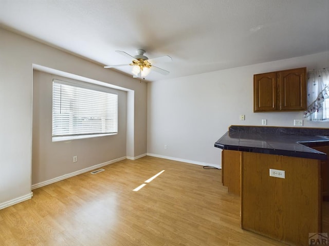 kitchen featuring visible vents, baseboards, tile countertops, light wood-style flooring, and brown cabinets