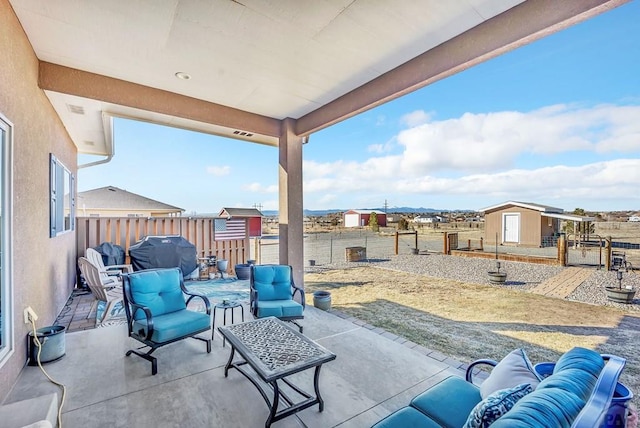 view of patio with an outbuilding, a grill, a fenced backyard, and outdoor lounge area