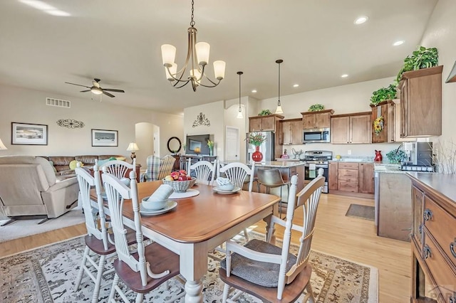 dining area featuring light wood-style floors, recessed lighting, visible vents, and arched walkways