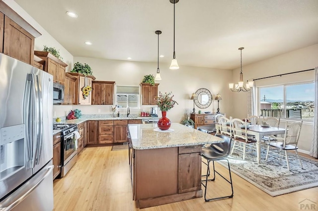 kitchen featuring a center island, stainless steel appliances, brown cabinetry, and light wood-style floors