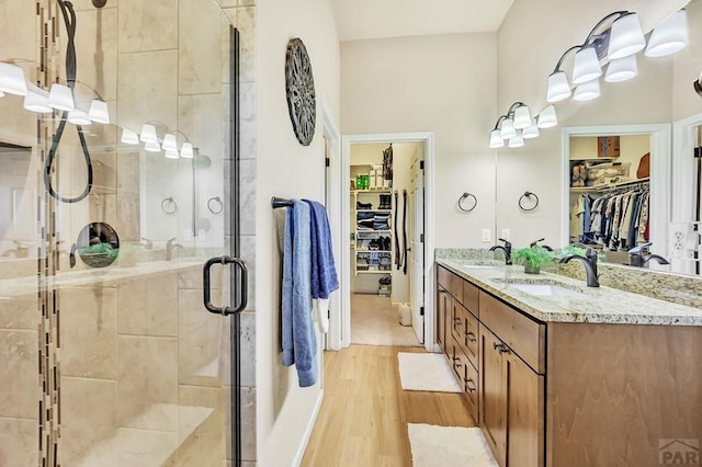 full bath featuring a sink, wood finished floors, a stall shower, and a spacious closet