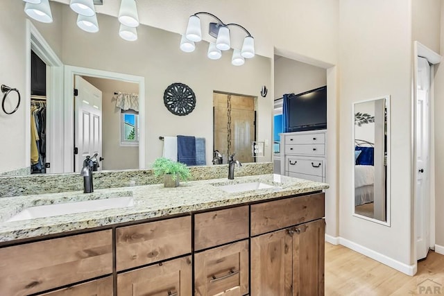 bathroom with double vanity, wood finished floors, a stall shower, and a sink