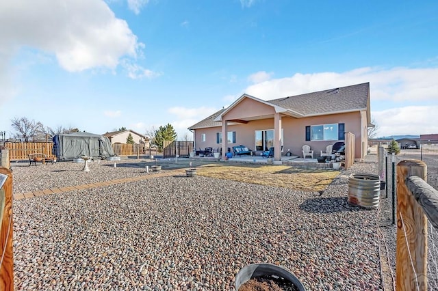 rear view of house featuring a patio area, stucco siding, roof with shingles, and fence