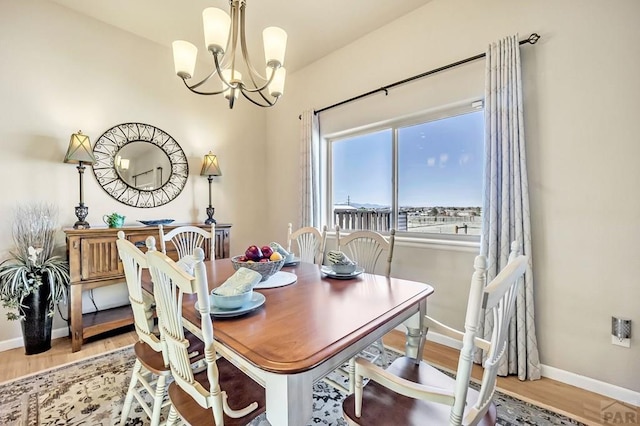 dining area featuring baseboards, a notable chandelier, and wood finished floors