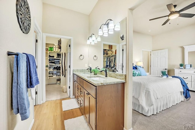 bathroom featuring a walk in closet, a ceiling fan, wood finished floors, connected bathroom, and vanity