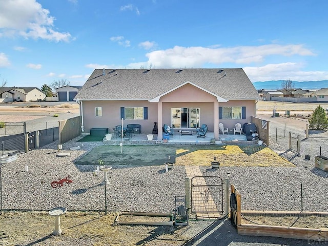 back of house with a patio area, stucco siding, a fenced backyard, and a gate