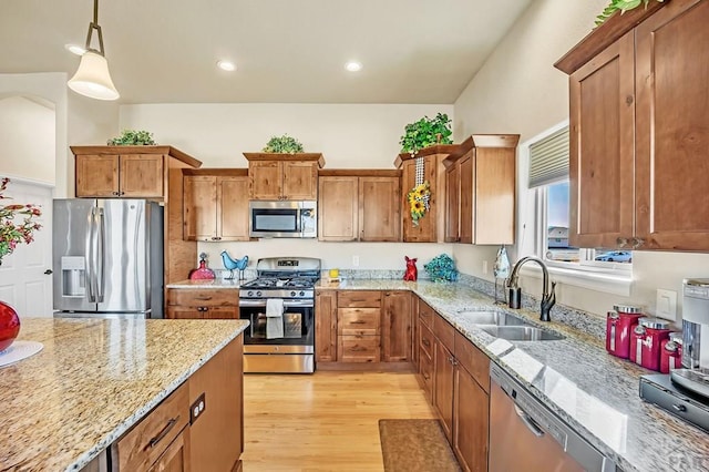 kitchen featuring a sink, light wood-type flooring, brown cabinets, and appliances with stainless steel finishes