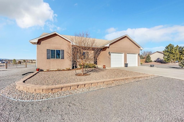 ranch-style house featuring stucco siding, a garage, and driveway