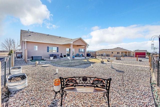 rear view of house featuring a patio area, stucco siding, a shingled roof, and a fenced backyard