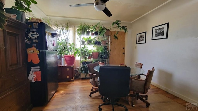 dining space featuring hardwood / wood-style floors, baseboards, a ceiling fan, and crown molding